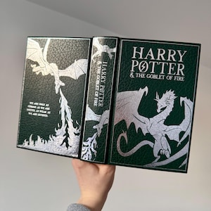 May include: A green leather-bound book with silver embossed details. The cover features a silver dragon with wings spread wide. The title "Harry Potter & The Goblet of Fire" is printed in silver lettering.