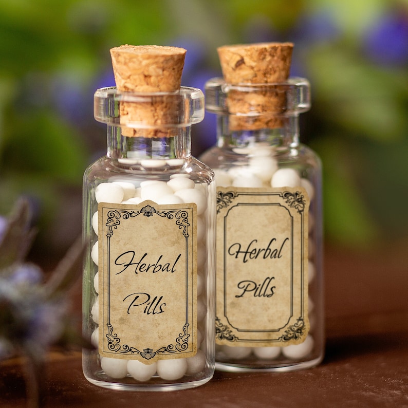 Puede incluir: Dos peque&ntilde;as botellas de vidrio con tapones de corcho llenas de p&iacute;ldoras blancas. Ambas botellas tienen etiquetas de estilo vintage que dicen "Herbal Pills".