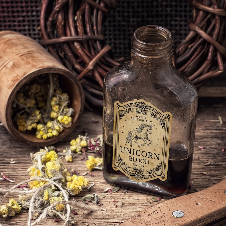 Pu&ograve; includere: Una bottiglia di vetro marrone con l'etichetta "Unicorn Blood" e un'illustrazione di un unicorno. L'etichetta recita anche "Mystic Apothecary". Erbe secche e un contenitore di legno su una superficie di legno, creando un'estetica da erboristeria mistica.