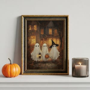 May include: Framed Halloween art print depicting three ghosts in white sheets, one wearing a witch's hat, holding a lantern and a jack-o'-lantern. The artwork is set against a backdrop of a spooky house and autumn foliage.
