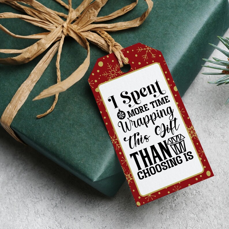 May include: Red and white gift tag with gold snowflakes and a white background. The text on the tag reads "I spent more time wrapping this gift than choosing it."