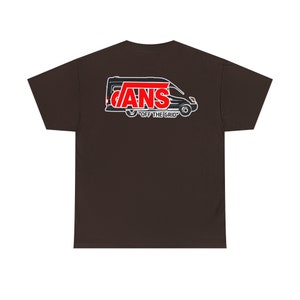 May include: A brown t-shirt with a black and white illustration of a van with the word "VANS" in red letters on the back. The text "OFF THE GRID" is printed below the van.