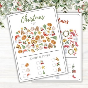 Puede incluir: Dos hojas de juego "I Spy" con temática navideña. La primera hoja tiene el texto "Christmas I Spy" con varias ilustraciones festivas como gorros de Papá Noel, casas de jengibre y campanas. La segunda hoja presenta ilustraciones similares, incluyendo bastones de caramelo y calcetines.