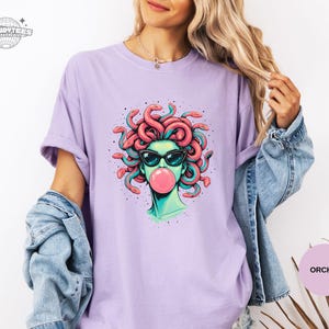 Orchid lavender Comfort Colors tee with the Medusa bubblegum portrait centered. The pastel purple gives the design a softer, feminine edge while keeping the art bold. Great for buyers who like witchy aesthetics in lighter tones.