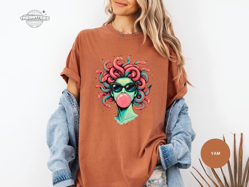 Yam orange-brown Comfort Colors tee with the Medusa bubblegum graphic centered. The warm shirt tone gives the art a retro, desert palette feel while the teal highlights keep it modern. Styled for an earthy, casual wardrobe.