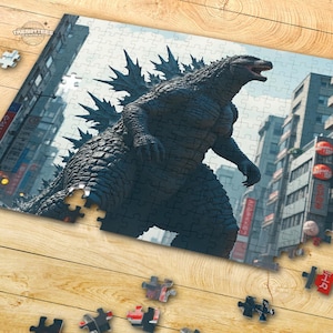 May include: A black and grey Godzilla monster puzzle with a city background. The puzzle is made up of many pieces and is partially assembled.