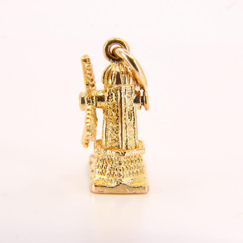 May include: A gold charm in the shape of a windmill. The charm is detailed with intricate carvings and has a small, spinning blade.