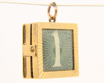 Può includere: Ciondolo quadrato color oro con un lato incernierato e un piccolo anello nella parte superiore. Il ciondolo presenta uno sfondo verde chiaro con il numero bianco "1" al centro. La cornice ha un design strutturato e scanalato.