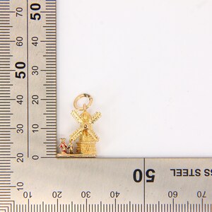 May include: Gold charm featuring a detailed windmill with red and white accents. The charm is approximately 1.5 inches tall and is perfect for adding a touch of Dutch charm to a necklace or bracelet.