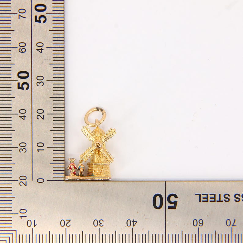 May include: Gold charm featuring a detailed windmill with red and white accents. The charm is approximately 1.5 inches tall and is perfect for adding a touch of Dutch charm to a necklace or bracelet.