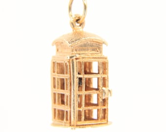 Puede incluir: Un charm dorado con forma de cabina telefónica británica clásica. El charm tiene forma rectangular con un techo curvo y una pequeña puerta. Las ventanas tienen un diseño de rejilla. Cuelga de un pequeño lazo.