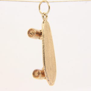 Peut inclure: Un pendentif en forme de skateboard de couleur or avec une surface texturée. Le pendentif comporte deux roues et une boucle pour l'attacher à une chaîne. Le skateboard est une réplique miniature d'un skateboard grandeur nature.
