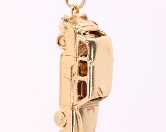 May include: A gold-colored charm in the shape of a bus, featuring detailed windows and wheels. The charm has a loop at the top for attaching to a necklace or bracelet. The bus charm is a miniature replica of a classic vehicle.