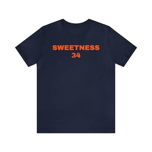 Pode incluir: Uma camiseta azul marinho com o texto "SWEETNESS 34" impresso em laranja na frente.