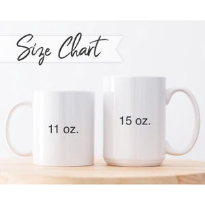 May include: Two white ceramic mugs of different sizes are displayed on a wooden surface. The smaller mug is labeled "11 oz." and the larger mug is labeled "15 oz." Above the mugs is the text "Size Chart" in a script font.