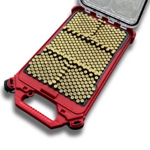 May include: A red, rectangular ammunition case with a clear lid, filled with numerous brass-colored bullet casings. The case has a handle and is designed for secure storage and transport of ammunition.