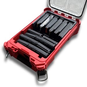 May include: A red, rectangular storage case with a clear lid, filled with black magazines. The case has a black interior with compartments to hold the magazines securely. The case has metal hinges and latches.
