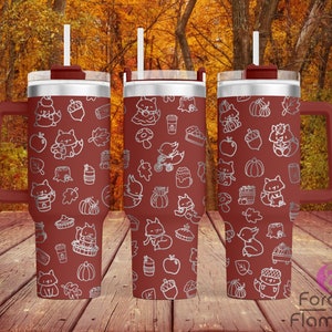 May include: Three stainless steel tumblers with a red base and a white design of foxes, pumpkins, acorns, and leaves. The tumblers have a handle and a straw.