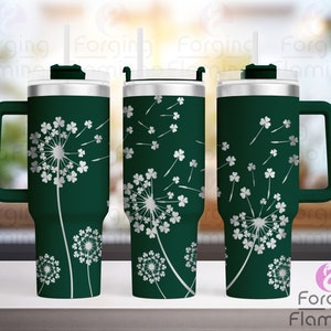 May include: A green stainless steel tumbler with a handle and a lid. The tumbler features a white design of dandelion flowers with clover leaves.