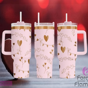 Puede incluir: Un vaso de acero inoxidable rosa con un diseño de corazón y flecha dorados. El vaso tiene una tapa y un asa.