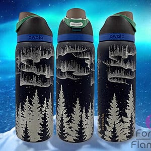 May include: Three black insulated water bottles with a white forest and aurora borealis design. Each bottle has a black lid with a green handle and the word "owala" printed on the side. The background is a blurred image of a snowy landscape.