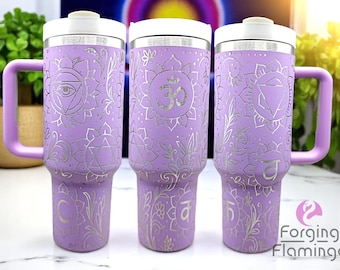May include: Three lavender travel mugs with white lids and handles. Each mug features silver floral and geometric designs, including chakra symbols. The mugs are decorated with the text "Forging Flamingo".