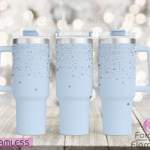 Puede incluir: Un vaso de acero inoxidable azul claro con una tapa plateada y un asa. El vaso tiene un diseño de estrellas plateadas sobre un fondo azul claro. El vaso se muestra desde tres ángulos diferentes.