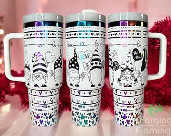 May include: Three white travel mugs with a Valentine's Day theme. Each mug features a different design of gnomes holding hearts, flowers, and balloons. The mugs have a silver iridescent finish and a black handle.