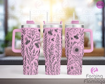 May include: Pink insulated tumbler with a handle, featuring a black floral and bee design. The tumbler has a pink lid and straw. The design includes various flowers and bees. The handle is also pink.
