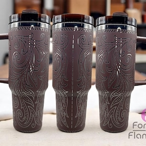 Pode incluir: Tr&ecirc;s canecas de viagem marrons com desenhos florais prateados e al&ccedil;as marrons. As canecas t&ecirc;m uma borda de a&ccedil;o inoxid&aacute;vel e uma tampa marrom escura. As canecas est&atilde;o em uma mesa de madeira.