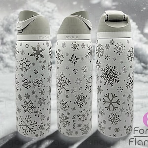 May include: Three white stainless steel water bottles with a snowflake pattern. The bottles have a gray lid and a gray band around the middle. The text "owala" is printed on the bottles.