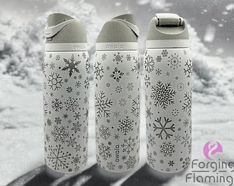 May include: Three white stainless steel water bottles with a snowflake pattern. The bottles have a gray lid and a gray band around the middle. The text "owala" is printed on the bottles.