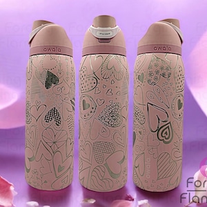 May include: Three pink water bottles with a silver heart pattern and the word "owala" printed on the front.