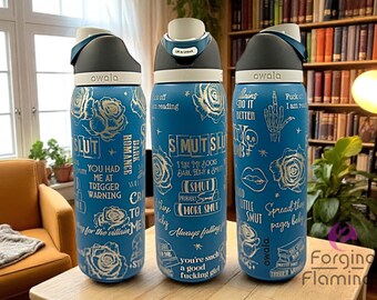 May include: Three blue Owala water bottles with silver text and rose illustrations. The bottles have various phrases like "SMUT" and "Dark Romance". Each bottle has a black and white lid.