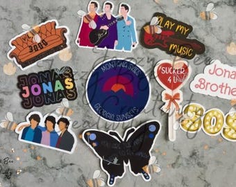 May include: A collection of stickers featuring the Jonas Brothers, including images of the band members, song titles, and phrases like "Sucker 4 U" and "Play My Music." The stickers have various shapes and colors.