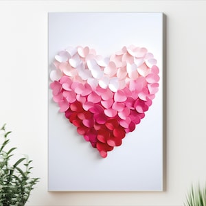 May include: A white canvas with a heart shape made of pink and red paper hearts. The hearts are arranged in a gradient from white to red.