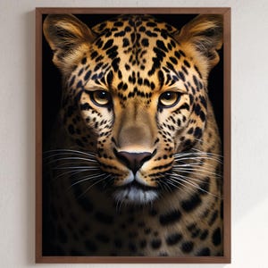 May include: A framed print of a leopard's face, close up. The leopard has a tan coat with black spots and yellow eyes. The background is black, and the frame is dark brown. The image is a portrait.