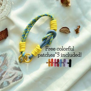 Nueva pulsera para teléfono hecha a mano con cuerda y bloques de colores en dos tonos en una combinación de amarillo y azul: correa para teléfono de ajuste universal y vibrante. Abalorio para bolso. Los mejores regalos festivos