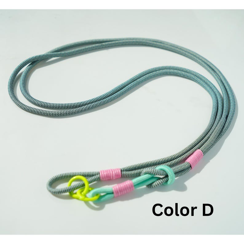 Pode incluir: Uma trela de corda longa com pintas cinzentas e brancas, com um anel amarelo n&eacute;on brilhante, detalhes em verde menta claro e enrolamentos de fio cor-de-rosa vibrante. O texto Color D est&aacute; impresso a preto no canto inferior direito.