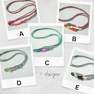 Pode incluir: Cinco cord&otilde;es rotulados de A a E, cada um apresentando uma corda com um la&ccedil;o atado e detalhes enrolados. O design A tem uma corda com detalhes em rosa, B apresenta laranja, C &eacute; verde menta com roxo, D &eacute; cinza com amarelo neon e E &eacute; cinza com preto.