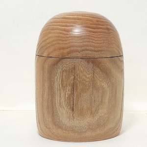 May include: A wooden box with a rounded lid. The box is made of light brown wood with a natural grain pattern.