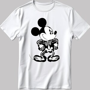 K&ouml;nnte beinhalten: Wei&szlig;es T-Shirt mit einem schwarz-wei&szlig;en Bild von Mickey Mouse, der als Skelett verkleidet ist. Mickey Mouse l&auml;chelt und hat die H&auml;nde in die H&uuml;ften gestemmt.
