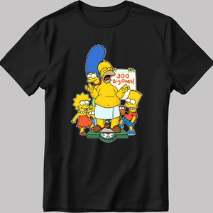 May include: A black t-shirt featuring a yellow cartoon image of the Simpsons family. Homer is standing on a scale that reads "300 Big Ones!" Marge, Lisa, and Bart are standing around him.