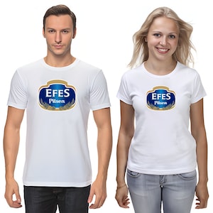 May include: White t-shirts featuring the "EFES Pilsen" logo in blue, gold, and white. The logo is an oval shape with the brand name and wheat illustrations. The shirts are short-sleeved and worn by two people.