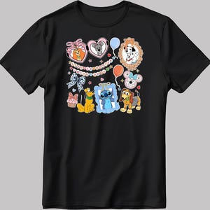 May include: Black t-shirt featuring colorful cartoon characters, including Lady and Tramp, 101 Dalmatians, Pluto, and Stitch. The design includes hearts, balloons, and the text "Happy Birthday with Dogs".