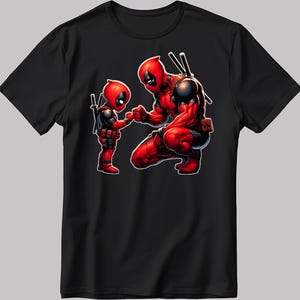 Può includere: T-shirt nera con un'illustrazione rossa e nera di due personaggi di Deadpool. Uno è in ginocchio e tiene la mano di una versione più piccola del personaggio. L'illustrazione ha uno stile fumettistico.