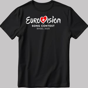 May include: Black t-shirt with a white graphic of the Eurovision Song Contest logo. The logo features a red heart with a white Swiss cross inside. The text "Eurovision Song Contest Basel 2025" is below the heart.