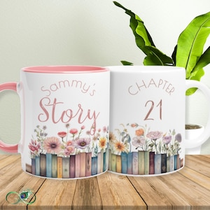 May include: Two white ceramic mugs with floral designs and text. One mug says "Sammy's Story" with a pink interior and handle. The other says "Chapter 21". Both mugs feature a row of books and colourful flowers.