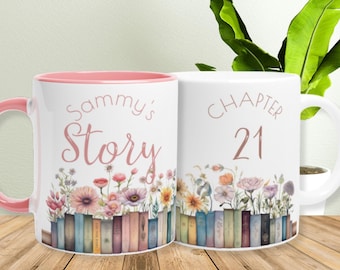 May include: Two white ceramic mugs with floral designs and text. One mug says "Sammy's Story" with a pink interior and handle. The other says "Chapter 21". Both mugs feature a row of books and colorful flowers.
