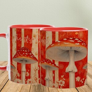 May include: Two ceramic mugs with a red interior and handle. The mugs feature a design of red and white mushrooms on a red and white striped background. The text "Aunty Jane" is written on the side of the mug.